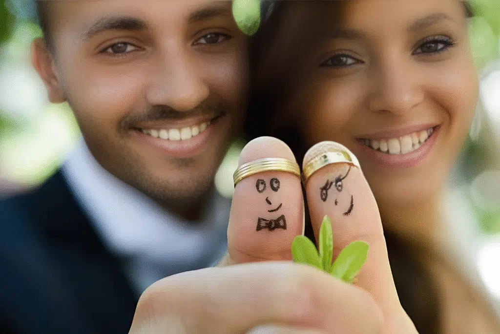 A man and woman joyfully hold wedding rings featuring smiley faces, symbolizing love and celebration on their special day.