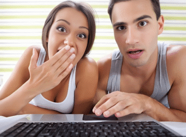 A man and woman engaged in a conversation about college life hacks, focused on a laptop screen.