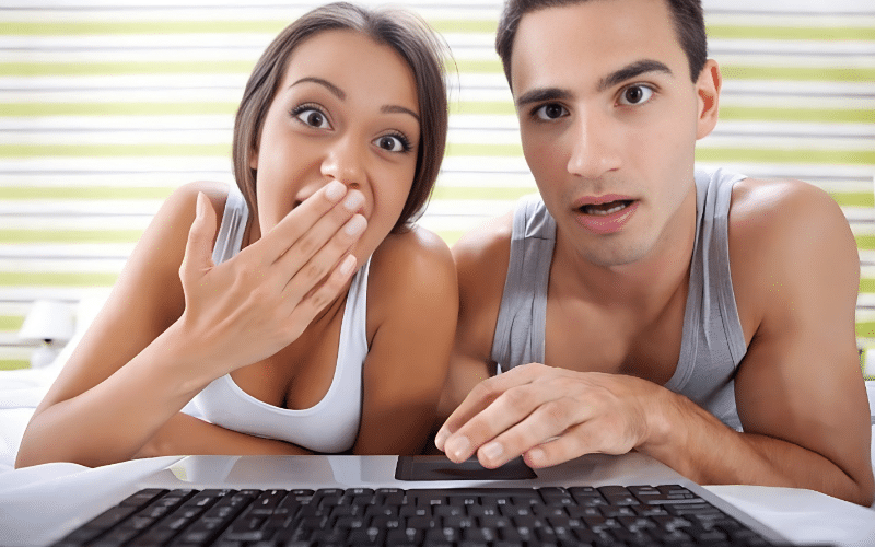 A man and woman engaged in a conversation about college life hacks, focused on a laptop screen.