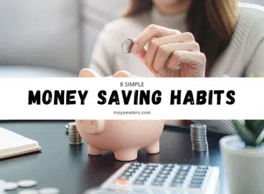 A person is inserting a coin into a piggy bank while sitting indoors, with a computer visible in the background. The individual is a woman, symbolizing money saving habits.