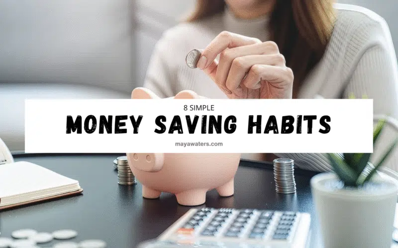 A person is inserting a coin into a piggy bank while sitting indoors, with a computer visible in the background. The individual is a woman, symbolizing money saving habits.