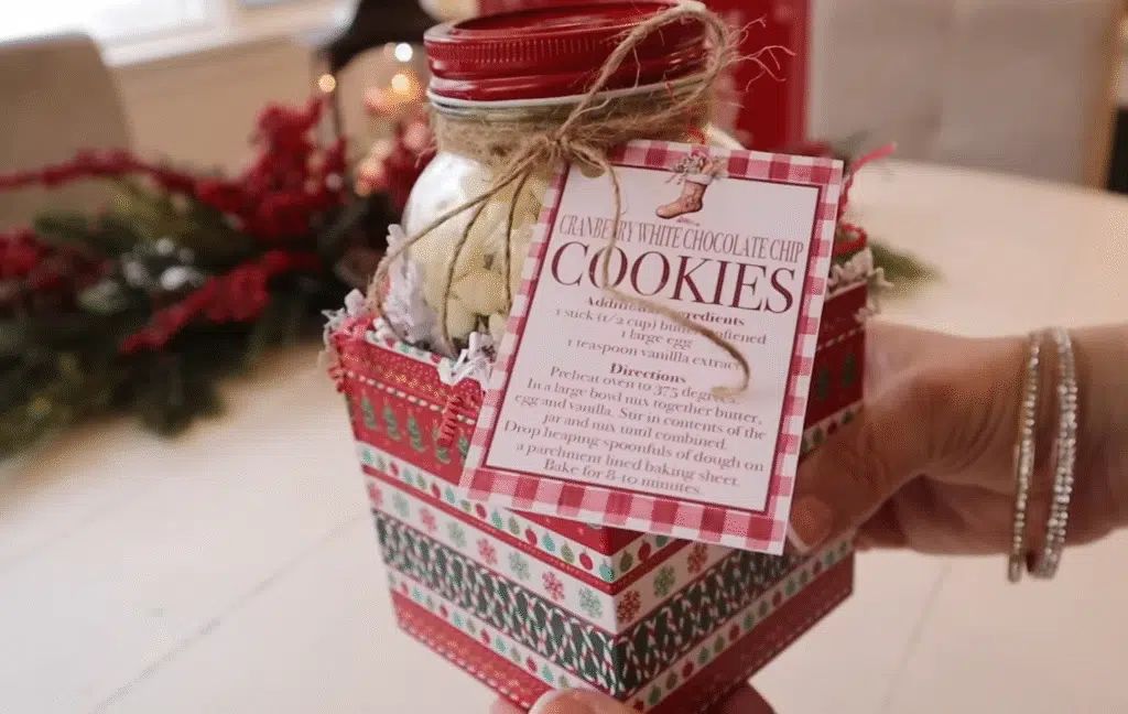 A person presents a Christmas cookie jar in front of a beautifully adorned Christmas tree, filled with holiday cookies.