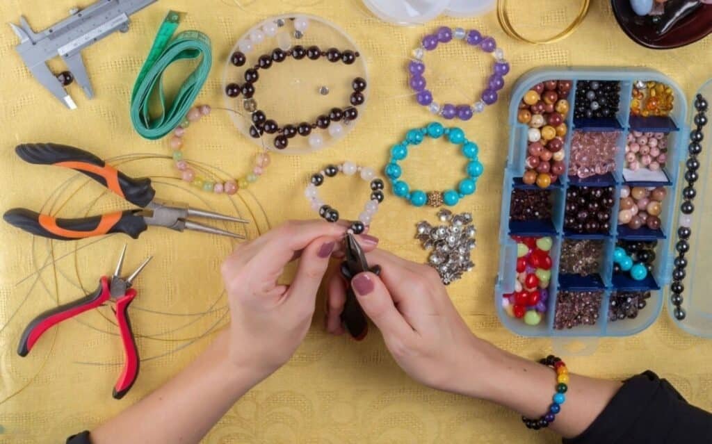 A person working on jewelry using various tools, including scissors, in an indoor setting to o Market Bracelets Without Feeling Pushy