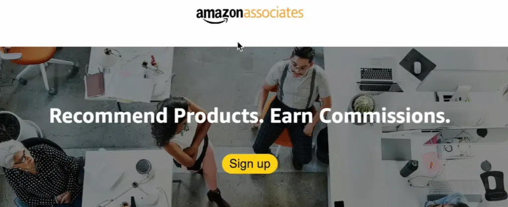 Amazon Associates homepage screenshot showing the slogan “Recommend Products. Earn Commissions.” with a yellow “Sign up” button and people working in an office environment.
