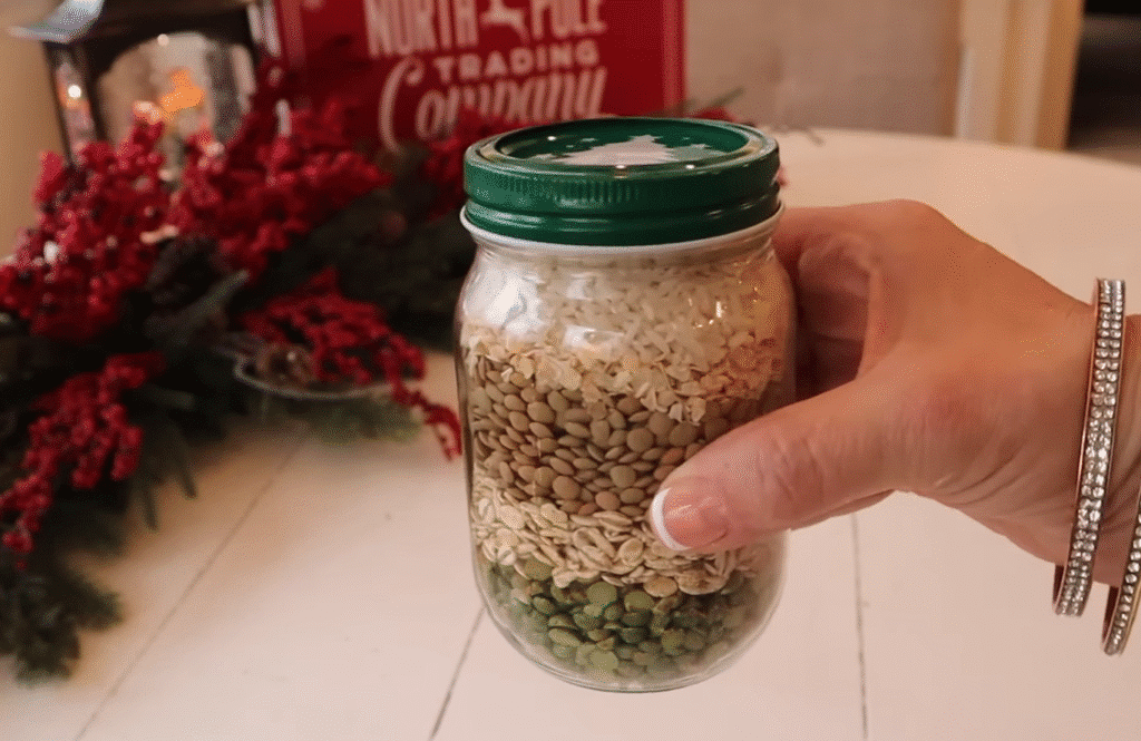 A person holding a jar filled with rice and beans labeled "Merry Christmas Soup.