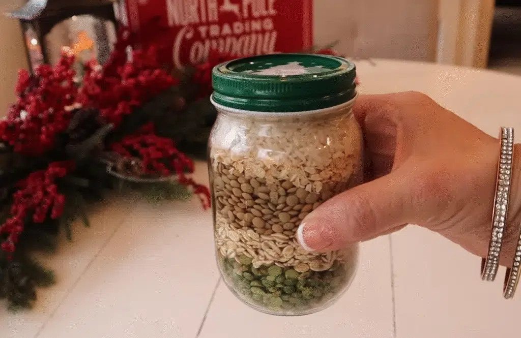 A person holding a jar filled with rice and beans labeled "Merry Christmas Soup.