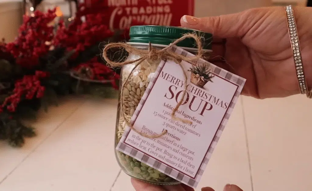 A hand grasping a jar of soup with a label reading "Merry Christmas Soup Gift," emphasizing a seasonal gift idea.