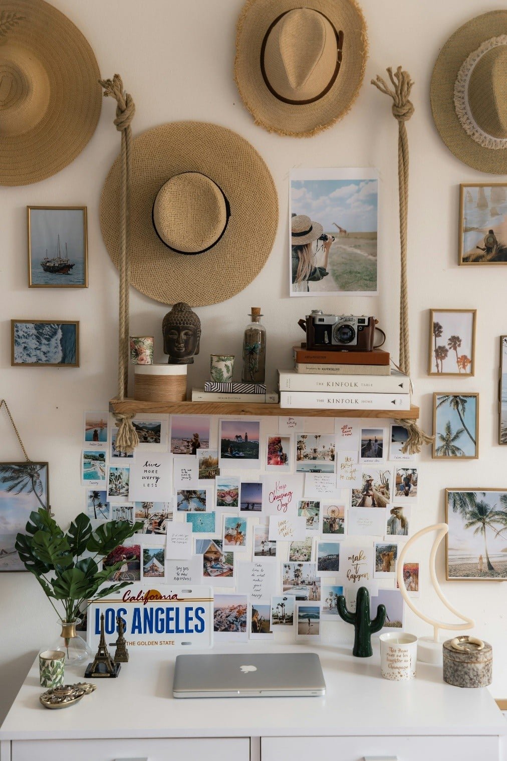 A workspace with a laptop, a hat, and decorative pictures on the wall, perfect for a mini phone wallpaper.