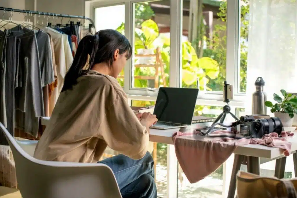 A woman at a desk with a laptop and camera, focused on her work related to high-ticket closing side hustles.