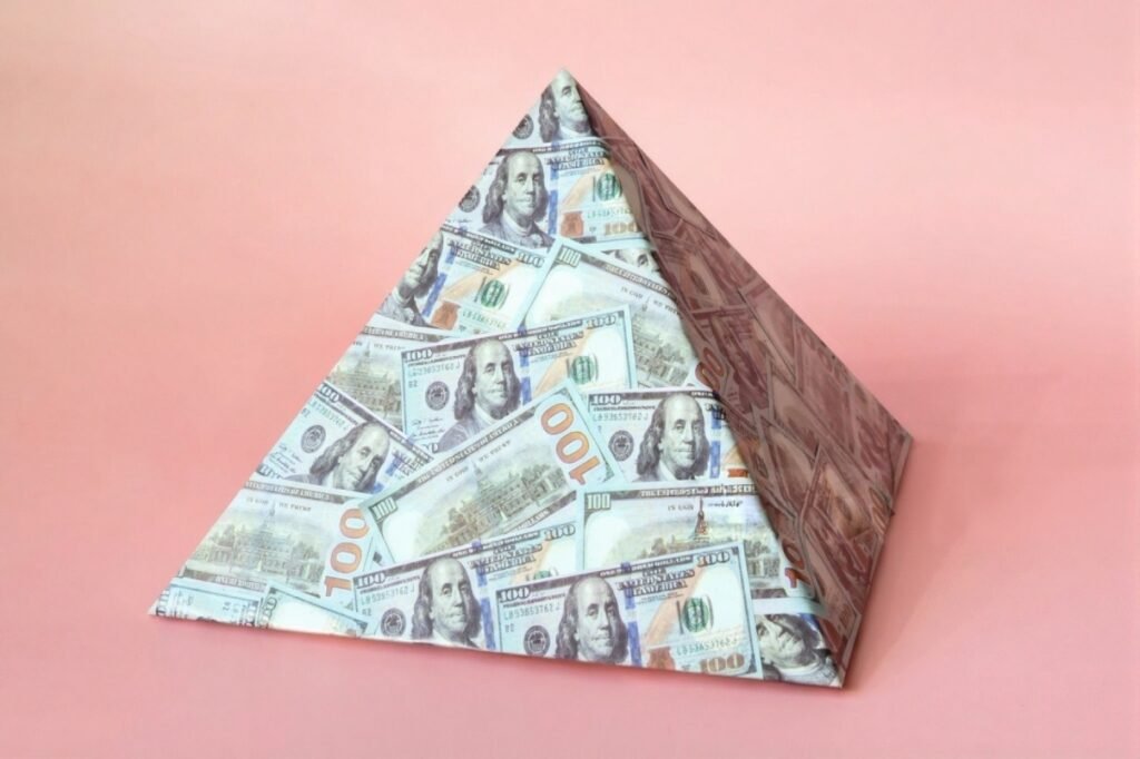 A money pyramid against a pink backdrop, illustrating the cautionary message about MLMs and side hustles to avoid.