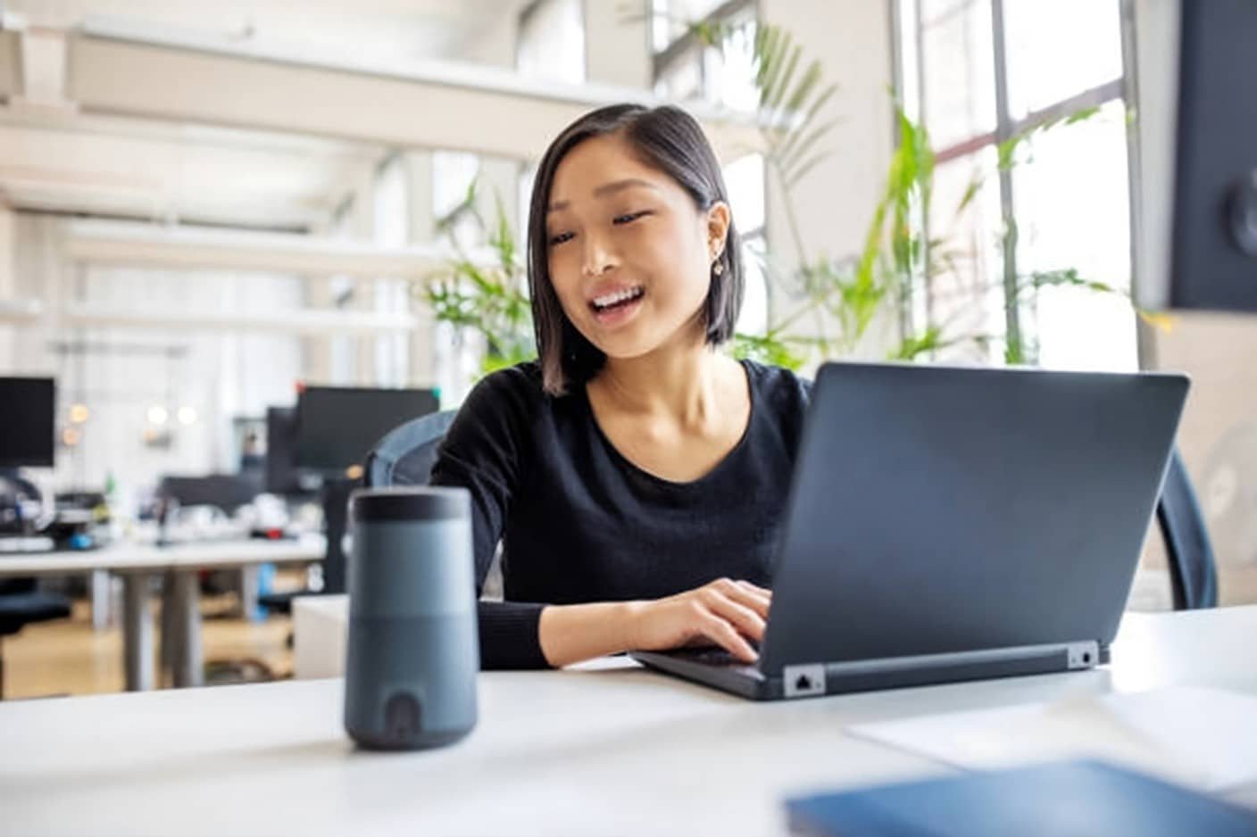 A smiling woman engages with her laptop, showcasing the Virtual Assistant Side Hustle Breakdown.
