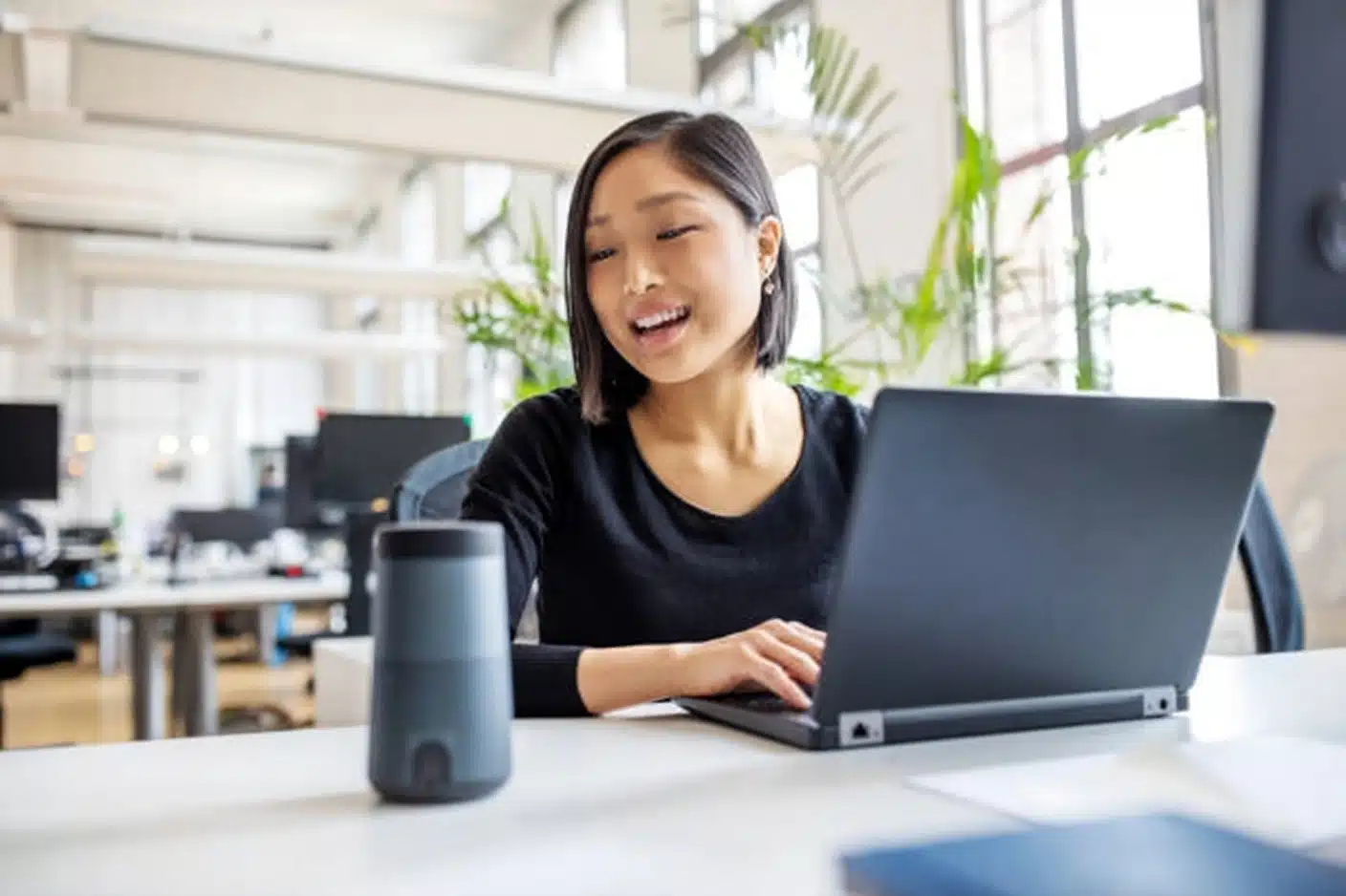 A smiling woman engages with her laptop, showcasing the Virtual Assistant Side Hustle Breakdown.