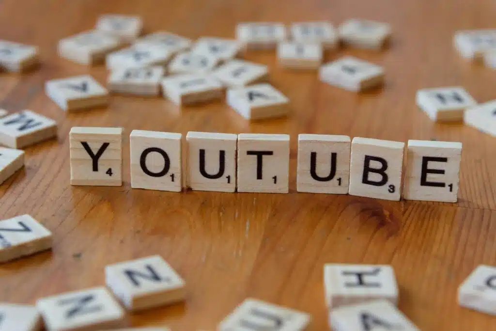 Wooden Scrabble tiles spelling the word YouTube on a table, representing YouTube channel names and video title ideas.