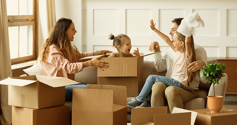 A family is seen moving boxes into their new home, symbolizing a fresh start and the joy of upgrading their living space.