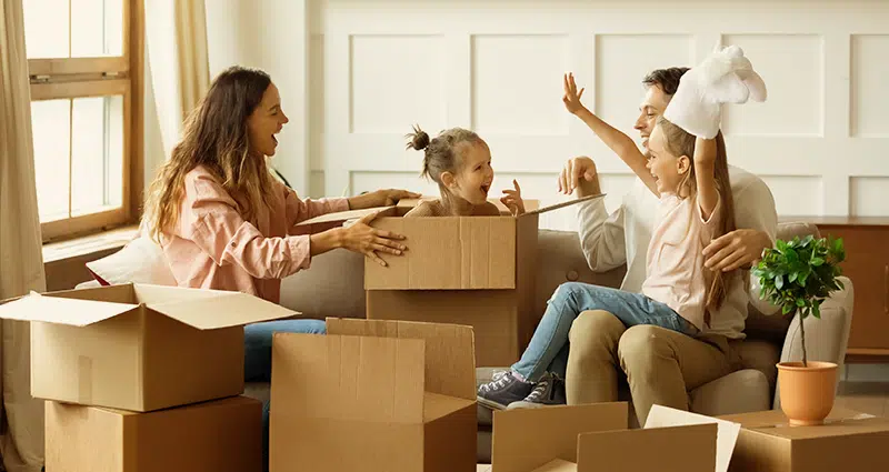 A family is seen moving boxes into their new home, symbolizing a fresh start and the joy of upgrading their living space.