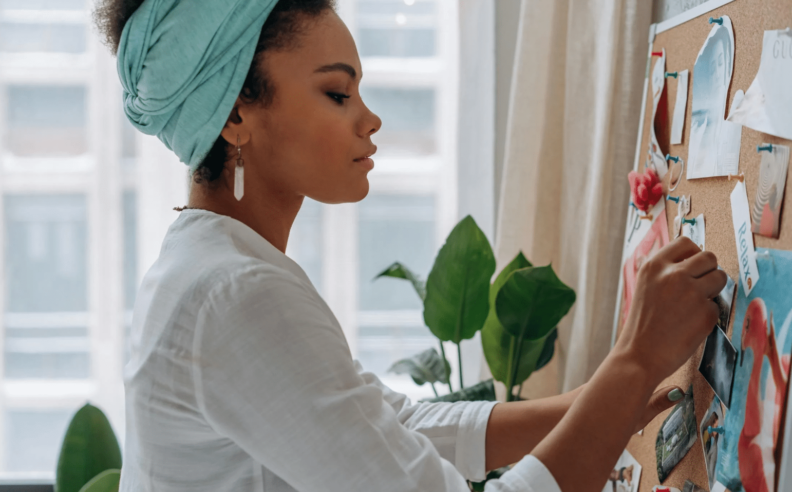 A woman paints a vision board on a bulletin board, surrounded by colorful images and inspirational quotes.