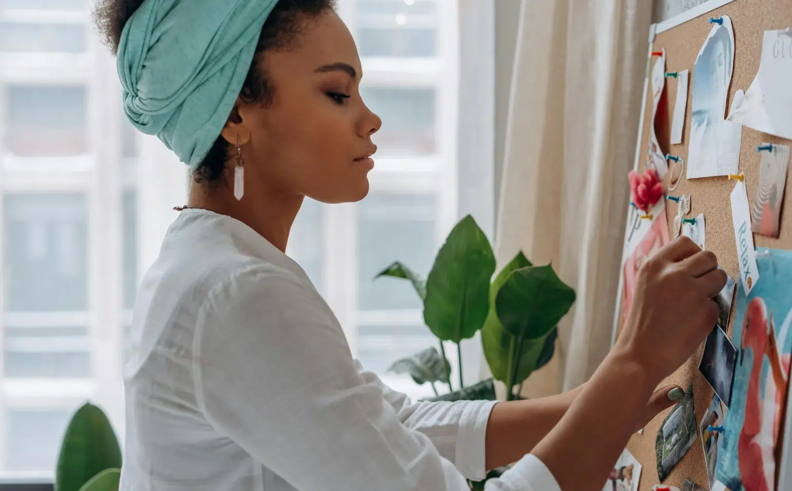 A woman paints a vision board on a bulletin board, surrounded by colorful images and inspirational quotes.