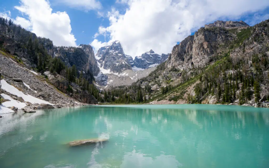 A serene lake surrounded by mountains, with the Grand Teton range visible in the background at Grand Teton National Park.