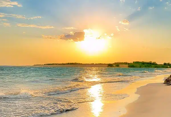A serene St. Augustine beach at sunset, with vibrant colors reflecting on the water and soft waves lapping at the shore.