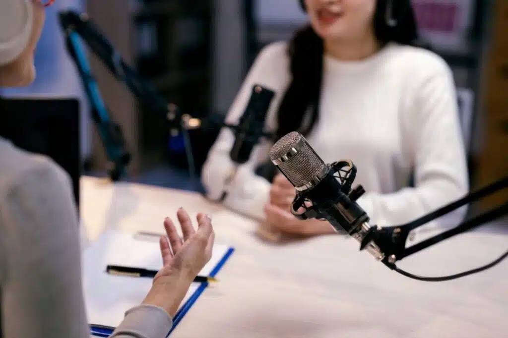 Two creators recording a podcast with microphones, discussing Content Creator Ideas for repurposing one idea into multiple content formats.