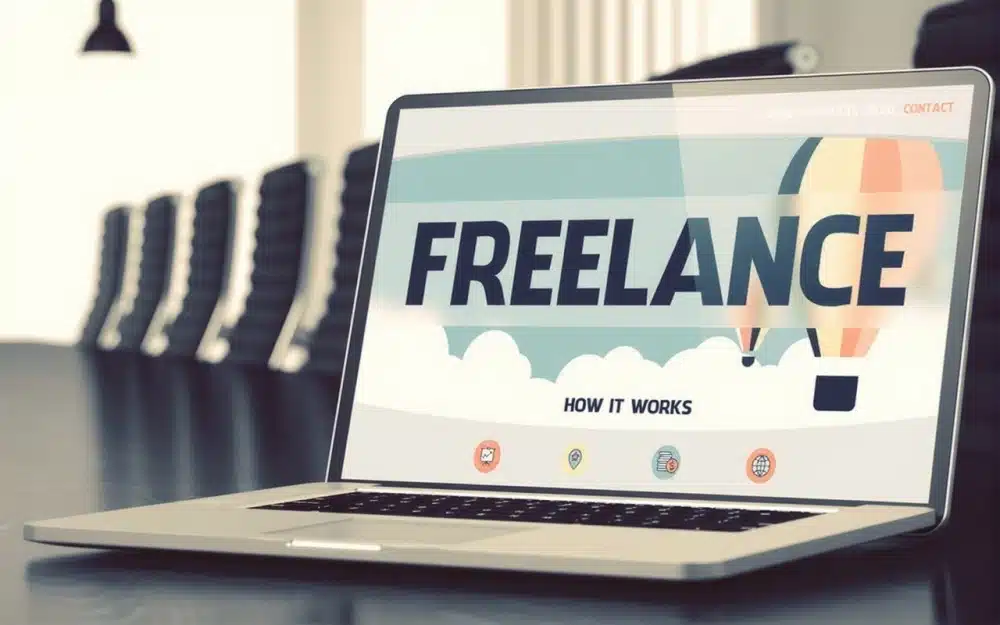 A laptop on a conference table displaying the word “Freelance” on the screen, symbolizing freelance writing as one of the Good Side Hustles for Women.