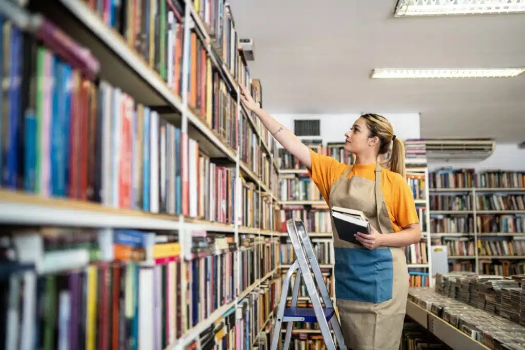 Teen organizing books on library shelves, representing safe and realistic Job Ideas for Teens 13 who want to start earning money through age-appropriate, parent-approved local work.