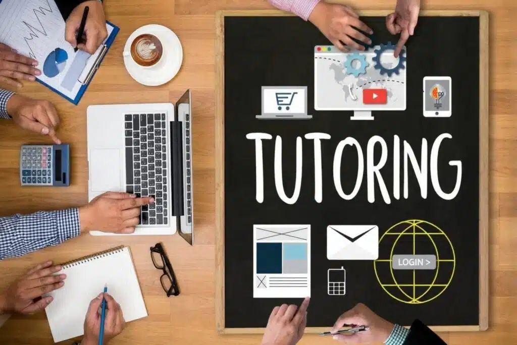 A top-down view of a workspace with a laptop, calculator, documents, and a chalkboard displaying the word “Tutoring,” representing online tutoring as one of the Good Side Hustles for Women.
