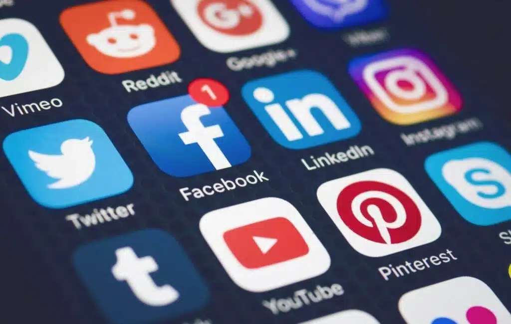 A close-up of a smartphone screen displaying popular social media app icons such as Facebook, Instagram, Twitter, LinkedIn, Pinterest, and YouTube, representing social media management as one of the Good Side Hustles for Women.