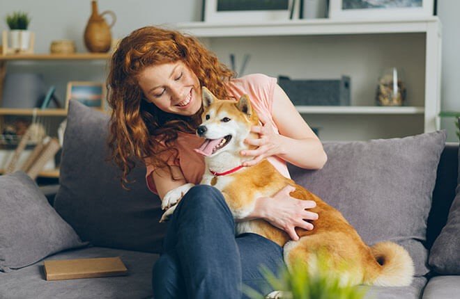 Woman cuddling a dog on a couch for tips on common pet sitting business mistakes to avoid.