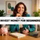 Woman learning how to invest money for beginners with laptop, notebook, and pink piggy bank on desk