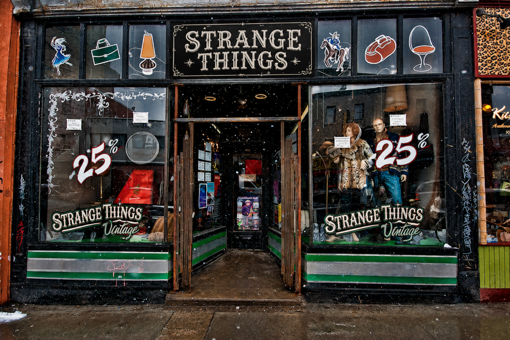 Exterior of Strange Things Vintage thrift store with vintage clothing displays and 25% sale signs.